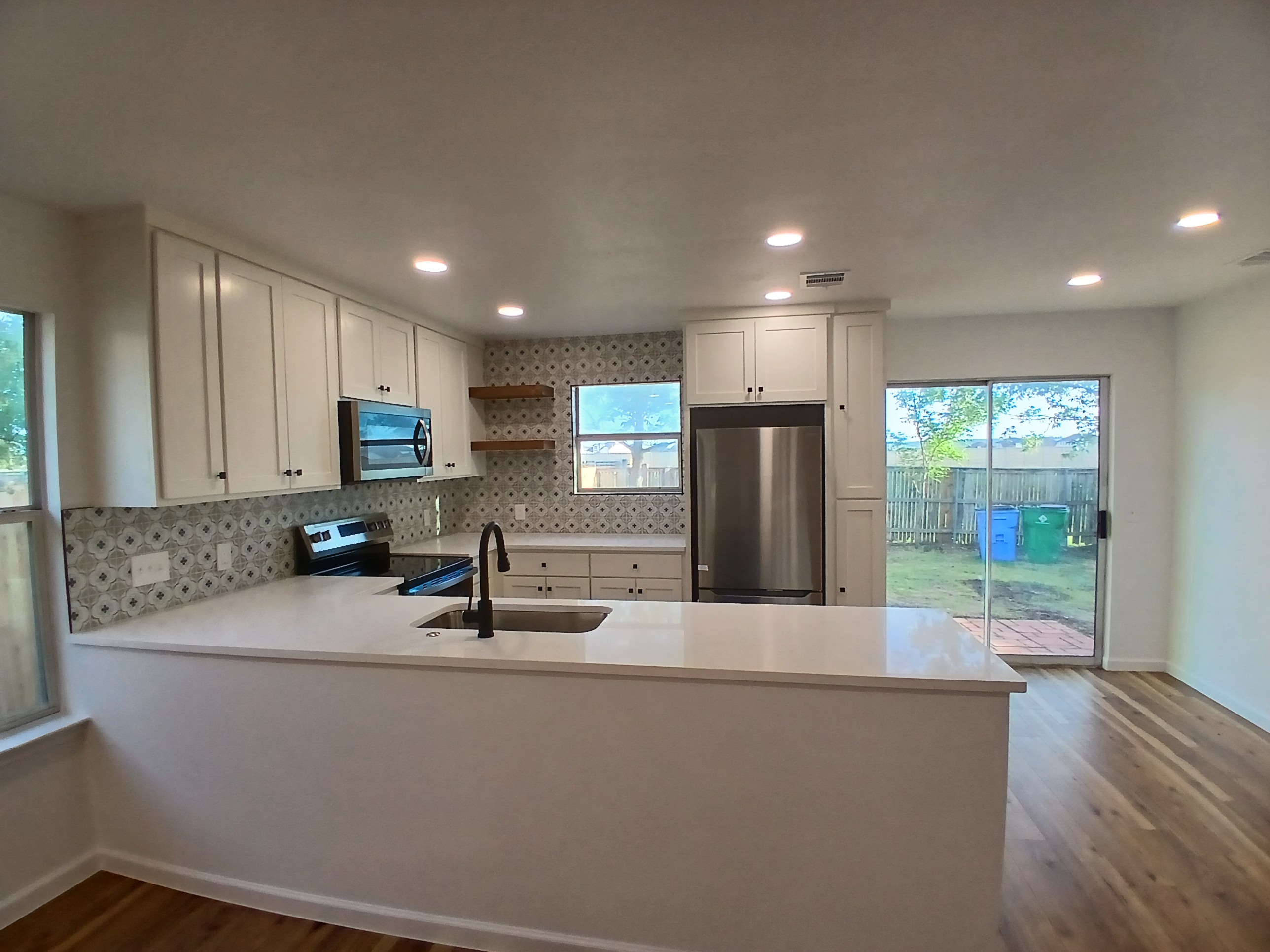 Kitchen remodel with white shaker cabinets, quartz countertops, and patterned tile backsplash