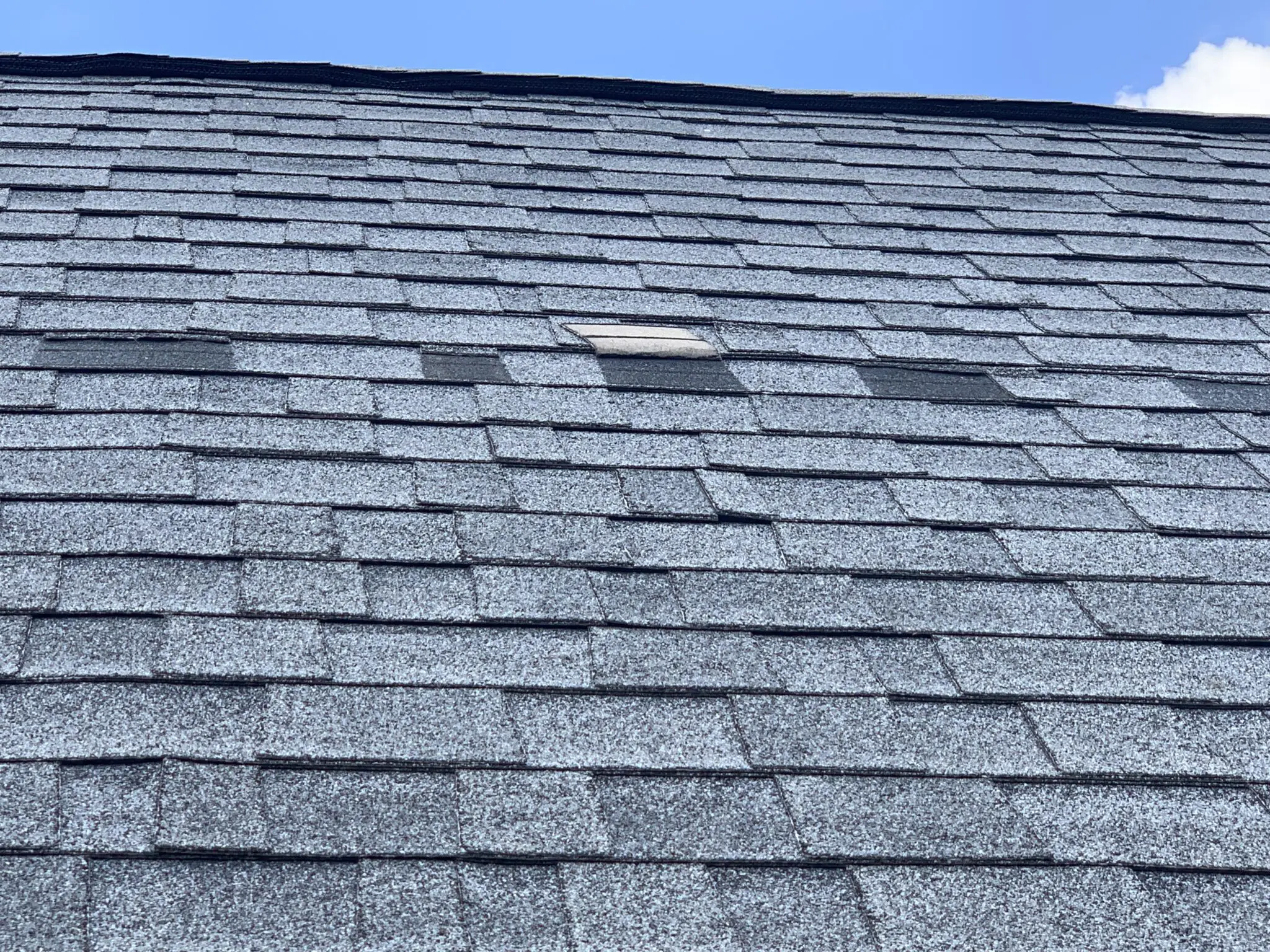Wind-damaged roof with missing shingles being repaired in Liberty Hill, Texas - River Ranch Roofing And Construction